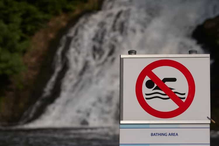 Drowning Hazard Sign In Front Of Waterfall